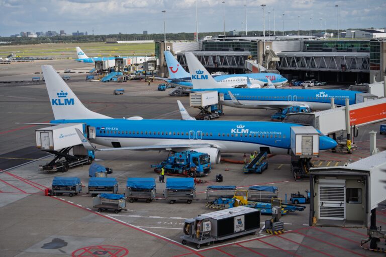 Why Do Airlines Fly with Empty Seats? KLM aircraft parked at Amsterdam Schiphol Airport, illustrating how hub airports support connecting flights and airline network planning.