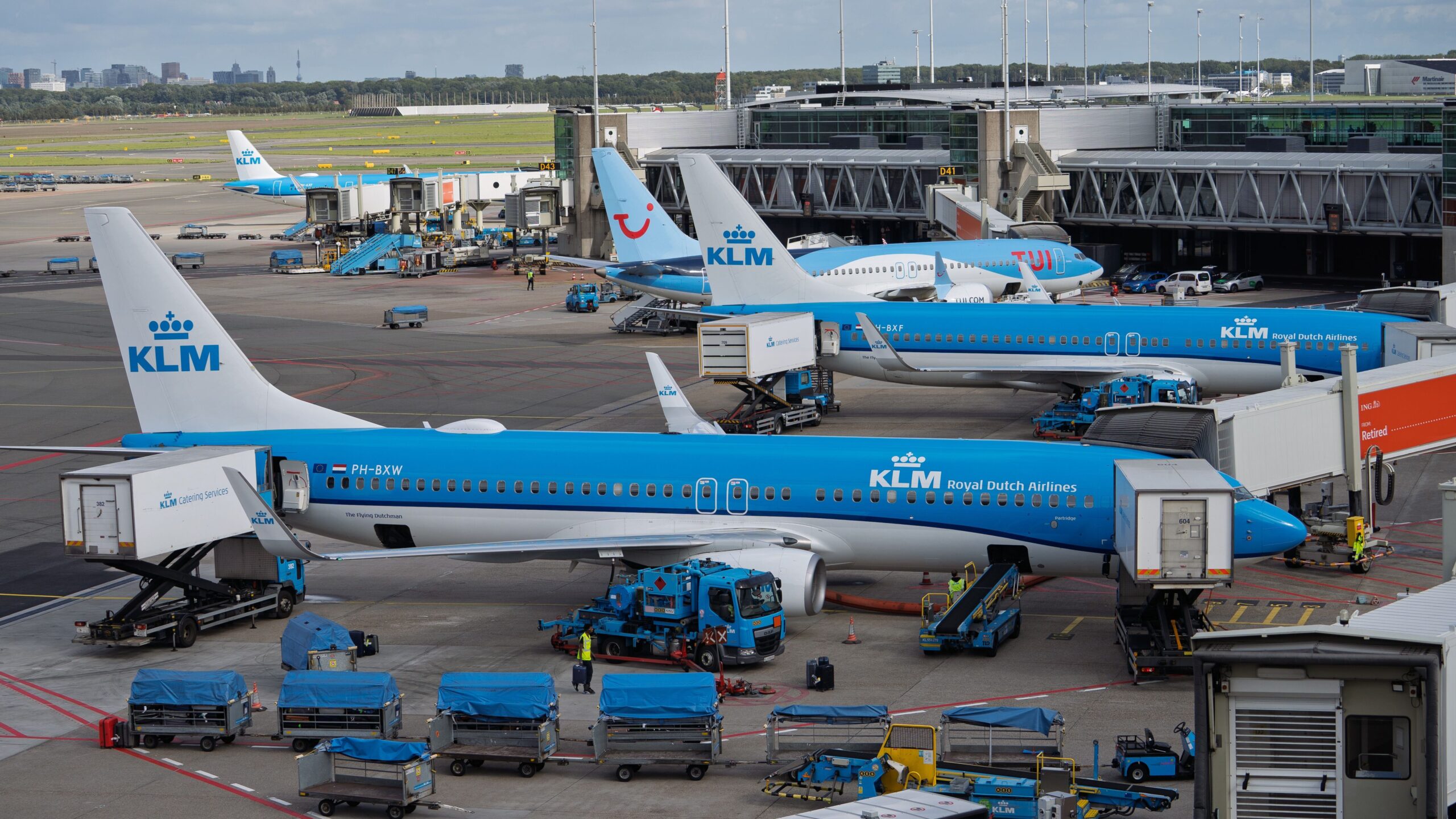 Why Do Airlines Fly with Empty Seats? KLM aircraft parked at Amsterdam Schiphol Airport, illustrating how hub airports support connecting flights and airline network planning.
