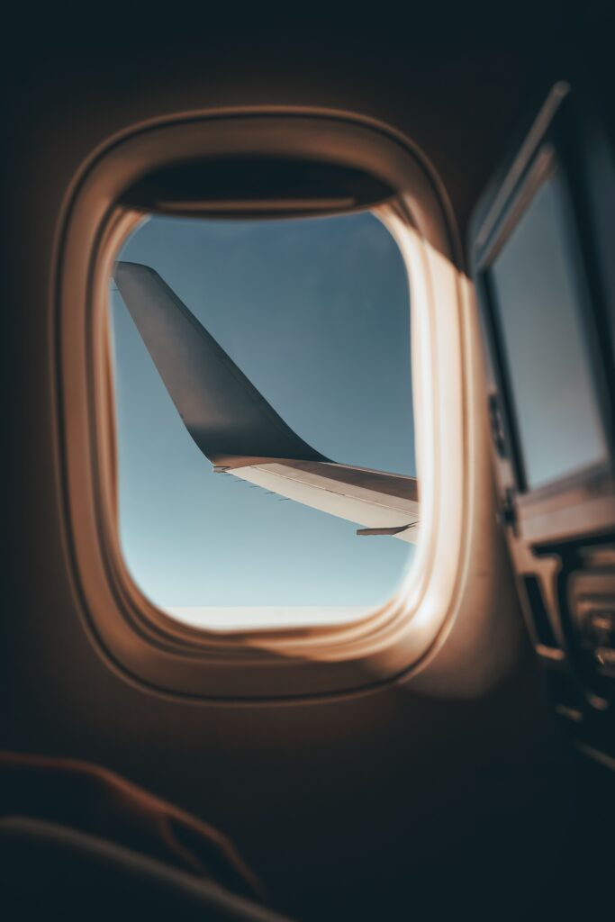 View of an airplane wing through a passenger window, representing smarter decisions about airfare, seats, upgrades, and award travel.