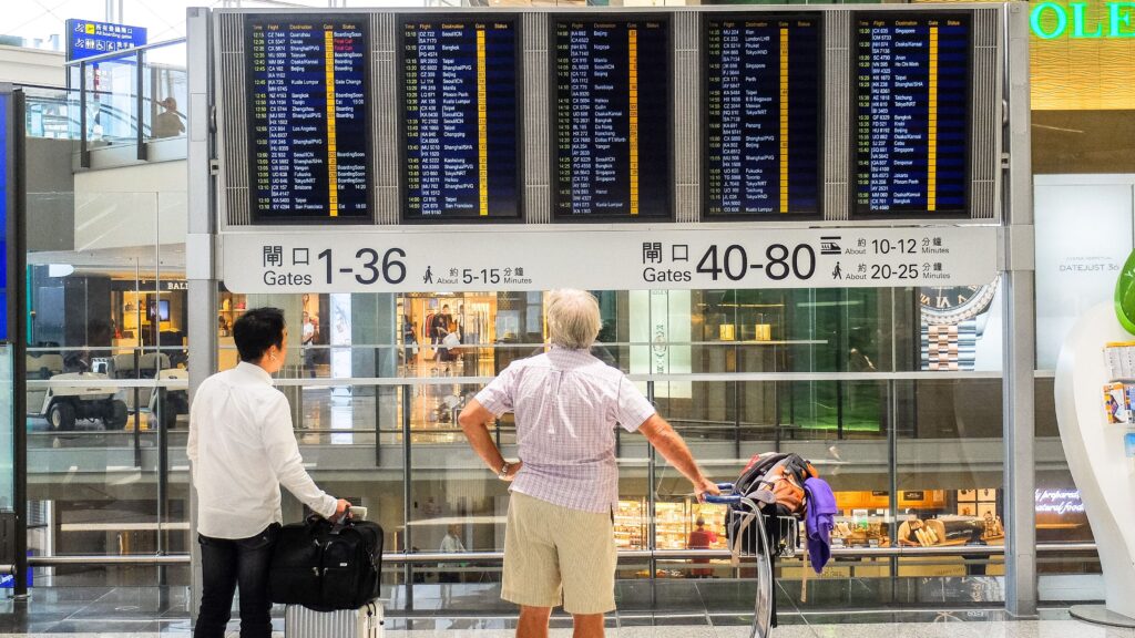 Travelers checking an airport departure board while waiting for their flights