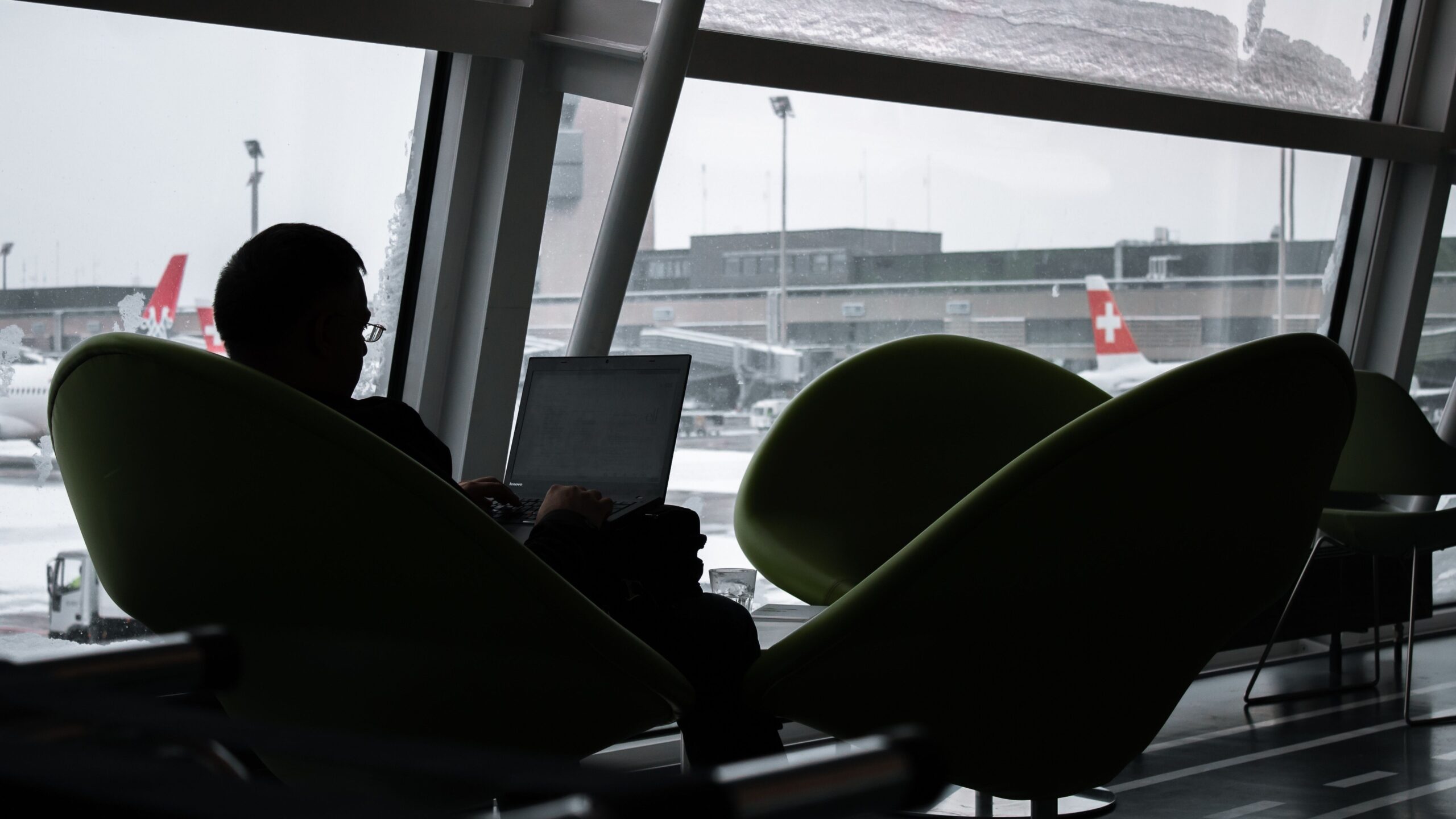 Traveler using a laptop at an airport while planning flights and managing airline loyalty status.