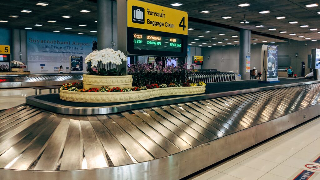 Airport baggage claim illustrating checked baggage considerations when booking positioning flights